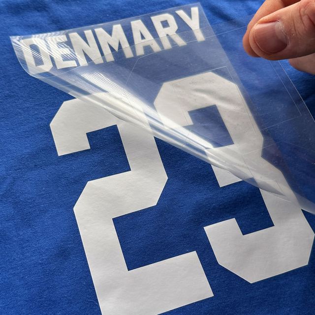 Clear sheet peeled off a white matte DENMARY 23 on a royal blue T-shirt
