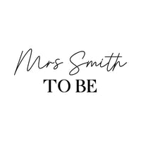 Flat black artwork on white: script 'Mrs Smith' over serif 'TO BE', personalised iron-on transfer design