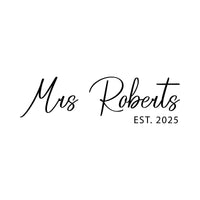 Flat black artwork on white: 'Mrs Roberts' in flowing script with 'EST. 2025', personalised wedding iron-on design
