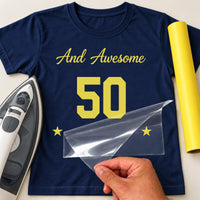 Navy T-shirt with yellow script and large number birthday lettering with stars, film being peeled