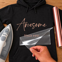 Awesome Since iron-on transfer: rose gold Awesome Since 1991 on a black hoodie, film being peeled