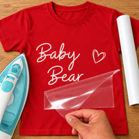 White script 'Baby Bear' with a small heart on a red T-shirt, iron-on vinyl mockup with carrier sheet lifting