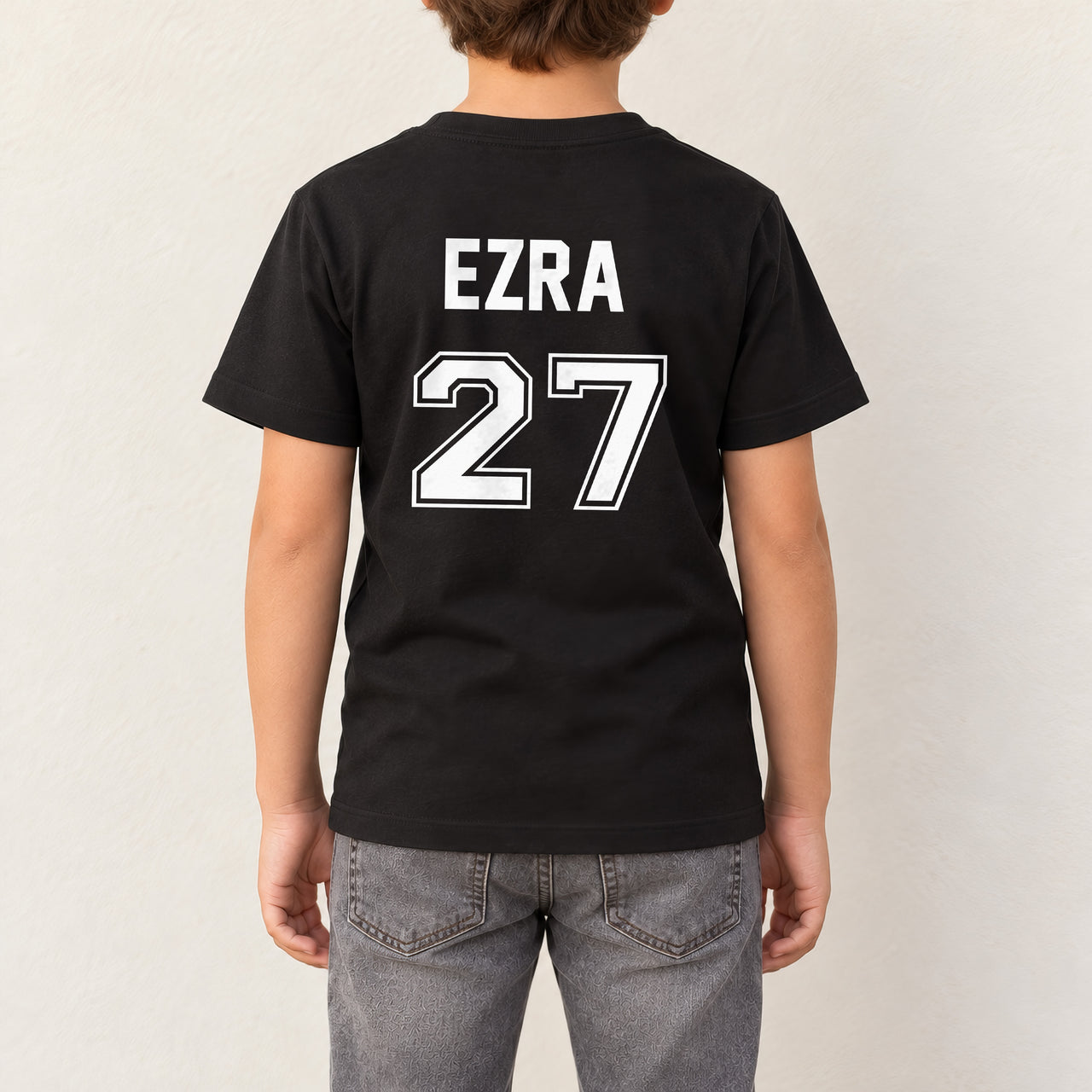 Baby Football Kit Name Number Iron-On Transfer, shown on a black kids t-shirt (back view)