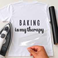 Baking Is My Therapy iron-on transfer: black BAKING is my therapy slogan on a white T-shirt, film being peeled