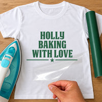 Baking With Love iron-on transfer: green HOLLY BAKING WITH LOVE with a star on a white T-shirt, film being peeled