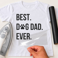 White T-shirt with black 'BEST. DOG DAD. EVER.' lettering, paw print as the O, film being peeled off - iron-on vinyl transfer