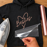 Black hoodie with rose gold script 'Besties' across a hand-drawn line heart, iron-on vinyl transfer