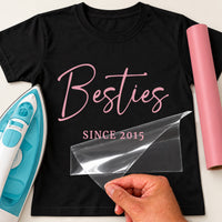 Black T-shirt with pink script 'Besties' and 'SINCE 2015', carrier film being peeled - personalised iron-on vinyl transfer