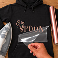 Black hoodie with rose gold 'Big SPOON' lettering, carrier film being peeled off - iron-on vinyl transfer