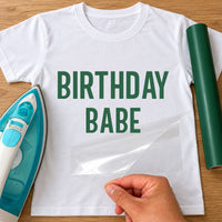 White T-shirt with green 'BIRTHDAY BABE' iron-on transfer in bold capitals, iron and green vinyl roll