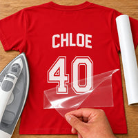Red T-shirt back with white 'CHLOE 40' name and number HTV transfer, carrier film lifted, white vinyl roll beside