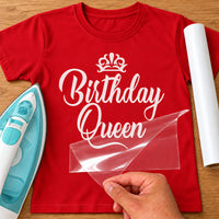 White 'Birthday Queen' script iron-on transfer with crown on a red T-shirt, film being peeled