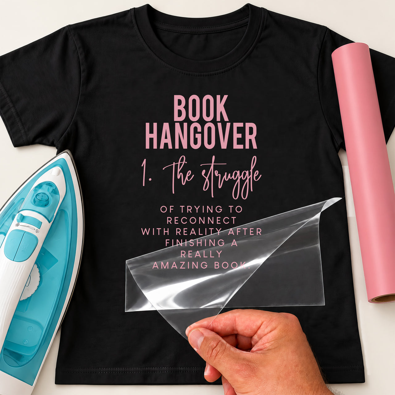 Black T-shirt with pink iron-on vinyl 'BOOK HANGOVER 1. The struggle' definition text, iron and pink vinyl roll