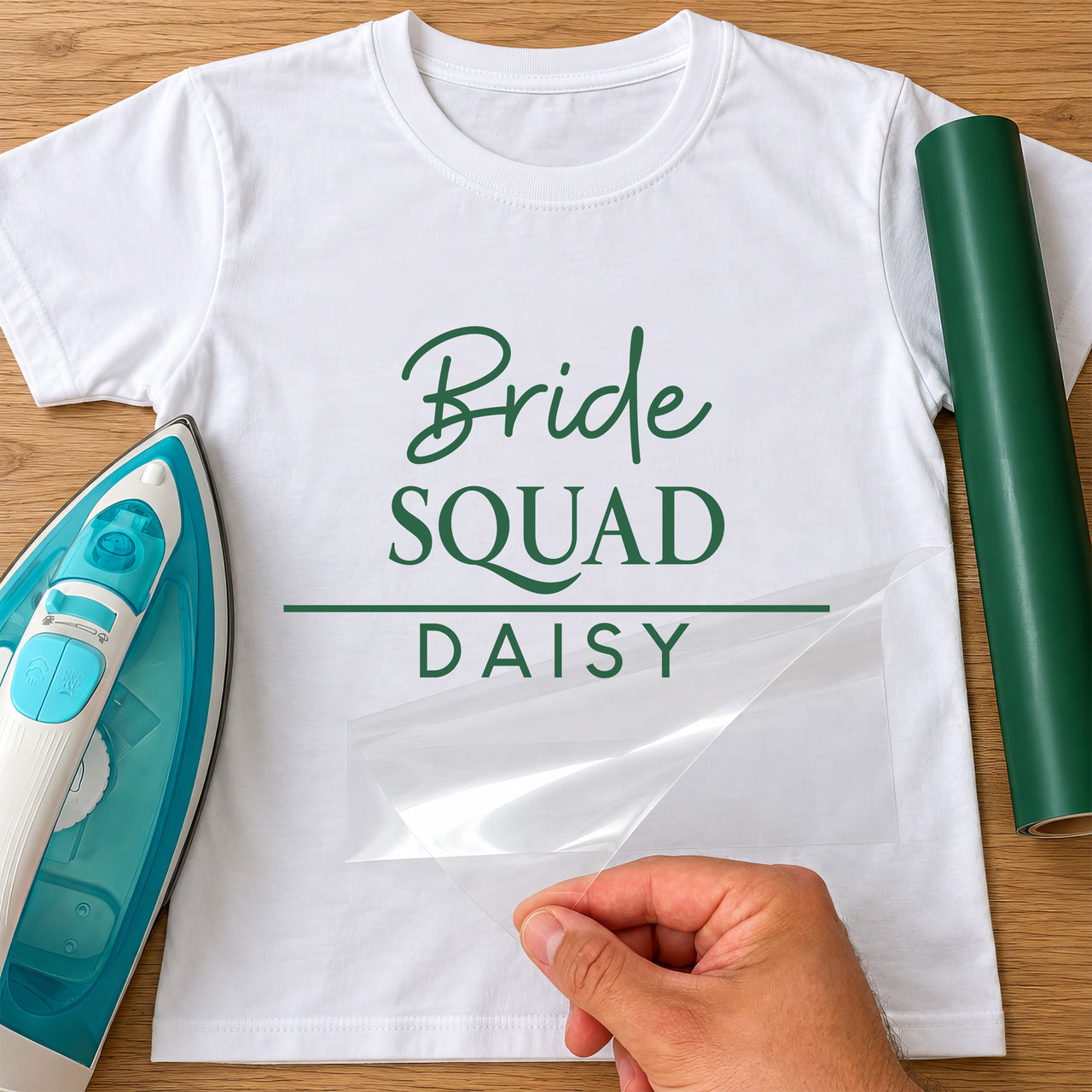 Mockup: white tee with green script 'Bride', 'SQUAD' and name 'DAISY' under a line, iron and green vinyl roll