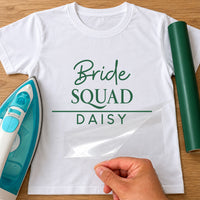 Mockup: white tee with green script 'Bride', 'SQUAD' and name 'DAISY' under a line, iron and green vinyl roll