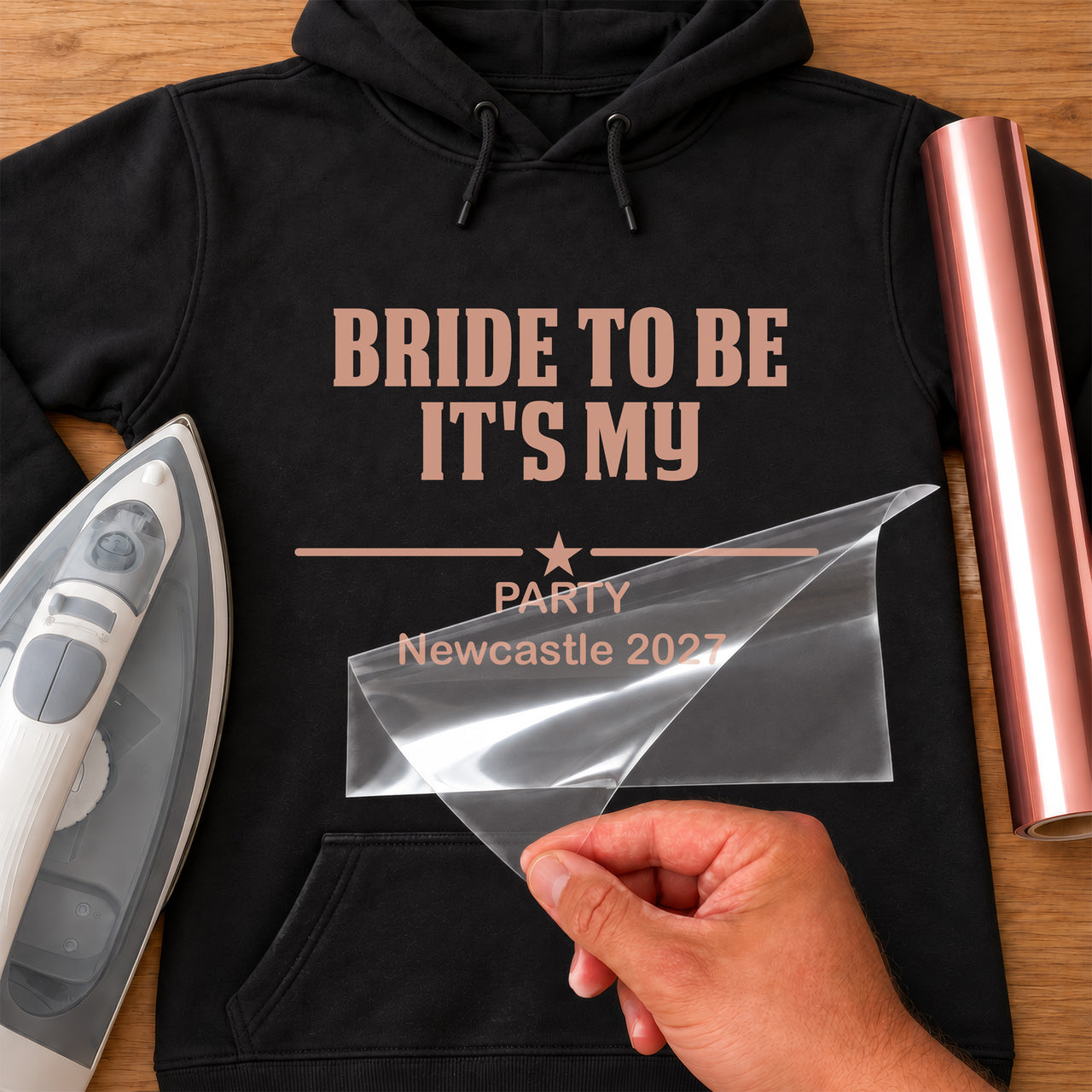 Black hoodie with rose gold iron-on vinyl 'BRIDE TO BE IT'S MY PARTY Newcastle 2027' with star