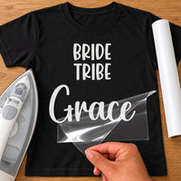 Bride Tribe iron-on transfer: white BRIDE TRIBE Grace on a black T-shirt, film being peeled