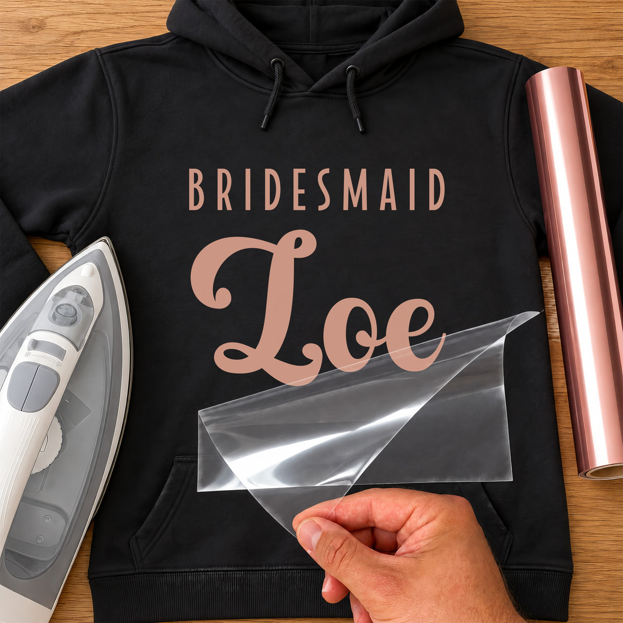 Black hoodie with rose gold 'BRIDESMAID' capitals and 'Zoe' script name iron-on transfer, iron and rose gold vinyl roll