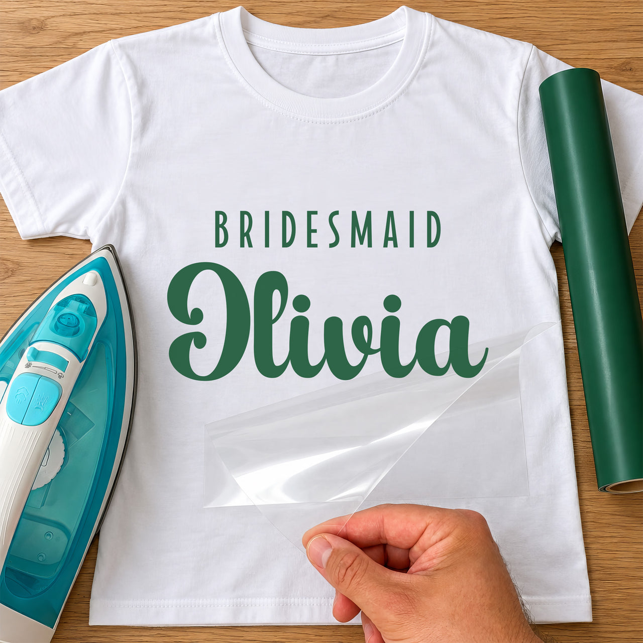 White T-shirt with green 'BRIDESMAID' and script 'Olivia' iron-on transfer, iron and green vinyl roll