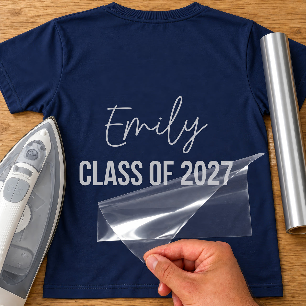 Back of navy T-shirt with silver 'Emily' script and 'CLASS OF 2027' capitals iron-on transfer, iron and silver vinyl roll