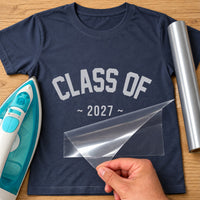 Navy T-shirt with silver vinyl arched 'CLASS OF' and '2027', iron-on vinyl transfer being peeled