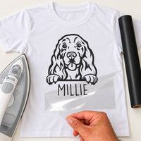 White T-shirt with black Cocker Spaniel peeking over a line and name 'MILLIE' iron-on transfer, iron and black vinyl roll