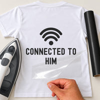 Back of a white T-shirt with black wifi symbol and 'CONNECTED TO HIM', carrier film being peeled off - iron-on vinyl transfer