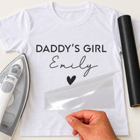 White T-shirt with black 'DADDY'S GIRL' capitals, 'Emily' script and a heart iron-on transfer, iron and black vinyl roll