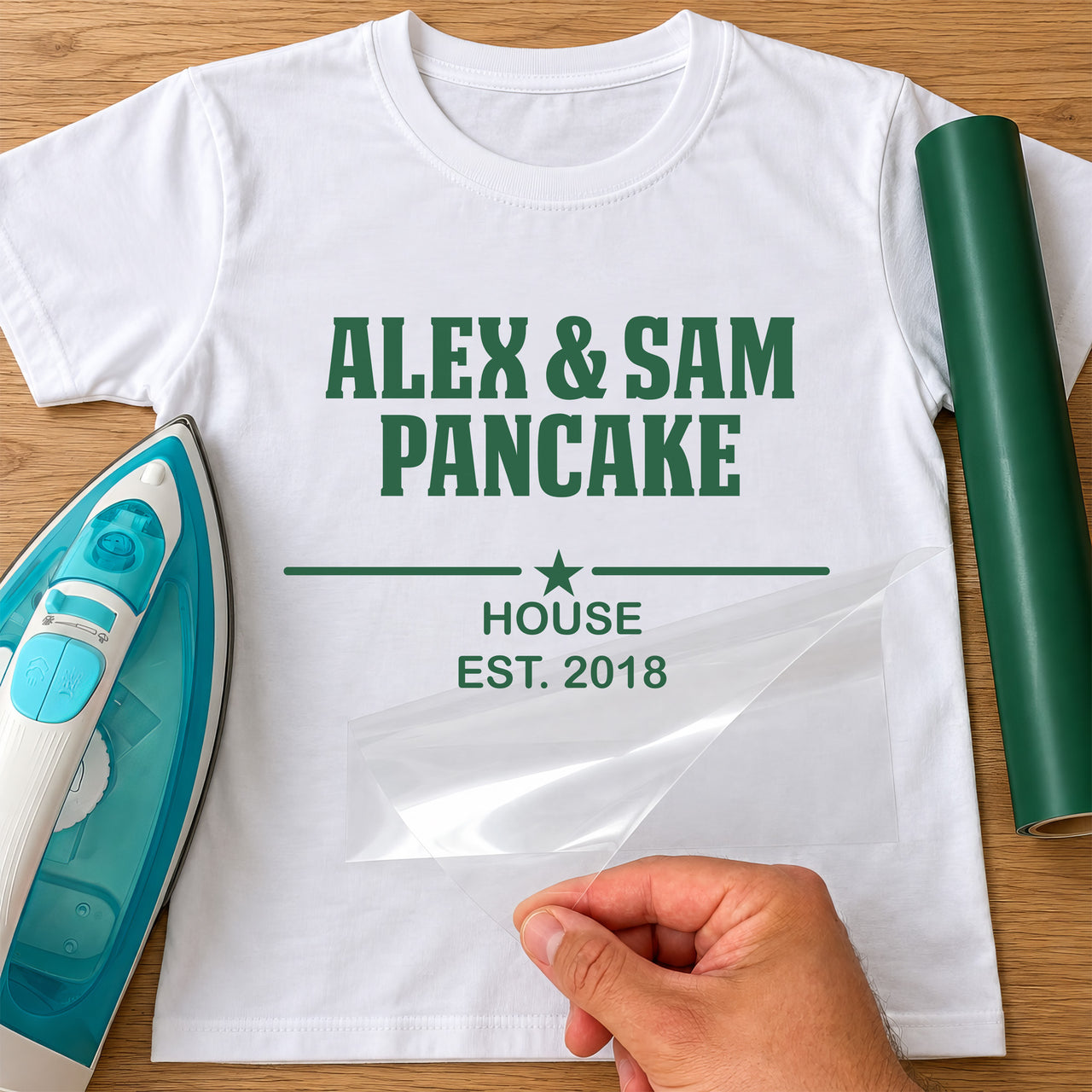 Pancake House iron-on transfer: green ALEX & SAM PANCAKE HOUSE EST. 2018 with a star on a white T-shirt, film being peeled