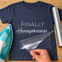 Navy T-shirt with silver 'FINALLY Honeymoonin' lettering, carrier film being peeled off - iron-on vinyl transfer
