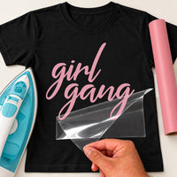Girl Gang iron-on transfer: pink girl gang script on a black T-shirt, film being peeled