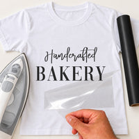 Handcrafted Bakery iron-on transfer: black Handcrafted BAKERY on a white T-shirt, film being peeled