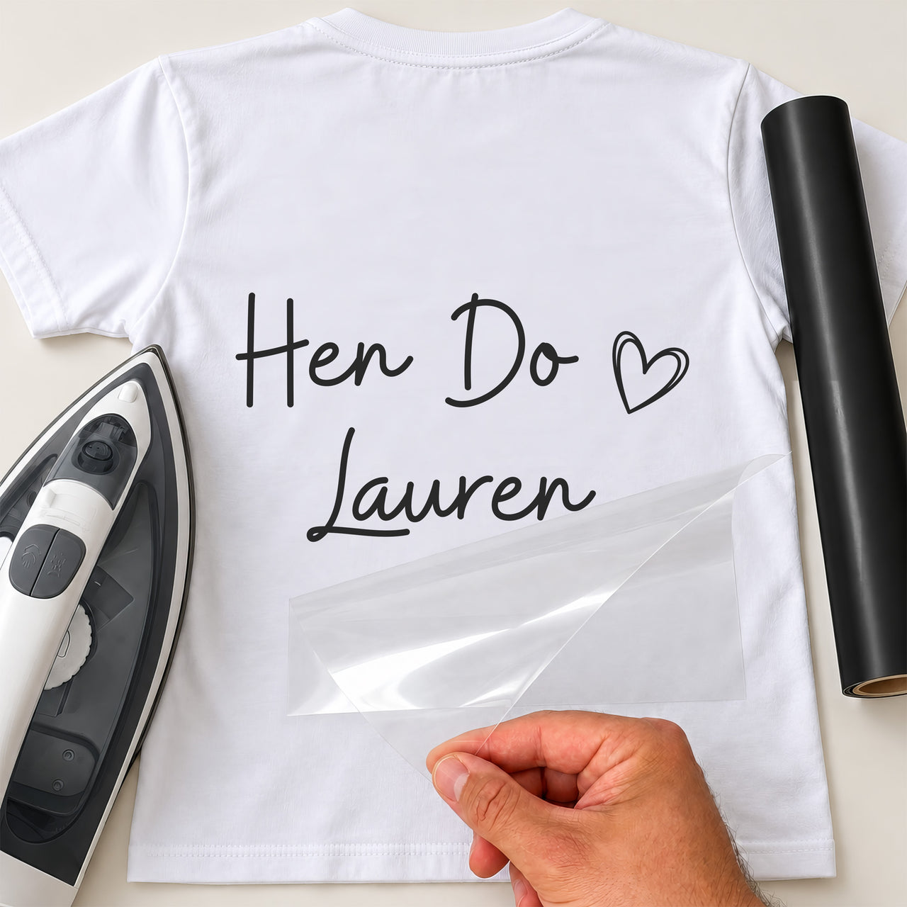 White T-shirt with black script 'Hen Do' iron-on transfer, outline heart and name 'Lauren', iron and black vinyl roll