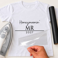 White T-shirt with black iron-on vinyl 'Honeymoonin' MR 2027', iron and vinyl roll beside