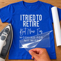 Blue T-shirt with white retirement slogan transfer, carrier film being peeled off next to an iron