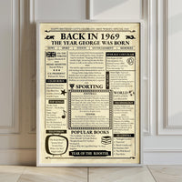 Large 1969 birthday newspaper poster in a white frame leaning against a panelled wall on a wooden floor