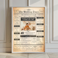 White framed 40th ruby wedding newspaper style poster leaning on a panelled wall on a wooden floor