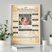 20th anniversary newspaper style poster in a white frame on a desk beside a plant and a grey lamp