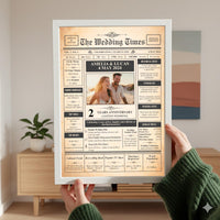 Hands in a green jumper holding a white framed anniversary newspaper print in a living room