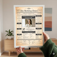Hands in a green knitted jumper holding a white framed 1989 photo front page poster in a living room