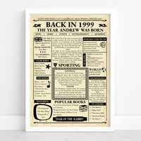 Framed 1999 retro newspaper print reading 'The year Andrew was born' on aged cream paper, standing against a white wall