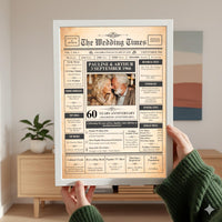 Hands holding a white framed 60th anniversary newspaper print in a living room with a sideboard