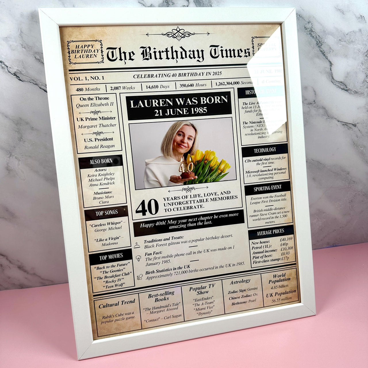 Birthday newspaper print in a white frame on marble: Lauren was born 21 June 1985, 40 years, photo with yellow tulips