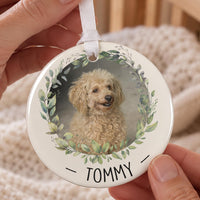Personalised pet bauble: ceramic ornament with a dog photo inside a green leaf wreath and the name TOMMY below