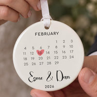 Calendar date ceramic ornament: February calendar with 13 in a red heart, Esme & Dan 2026, held in hand