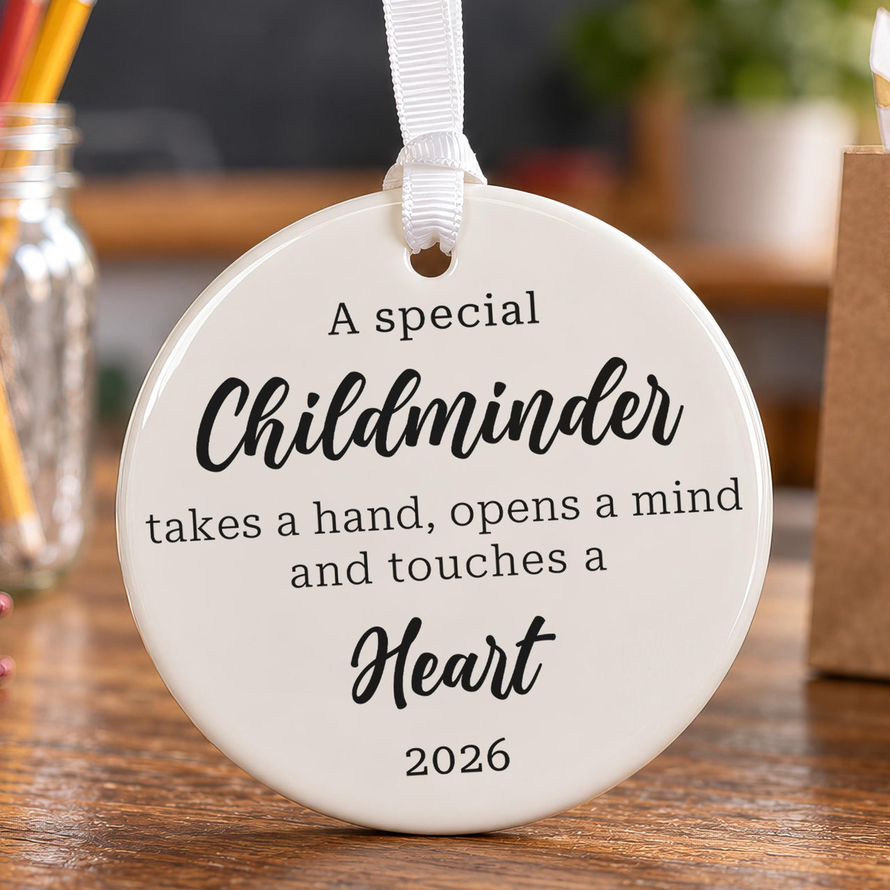 Childminder ceramic ornament: round white disc with black quote takes a hand, opens a mind and touches a heart, 2026