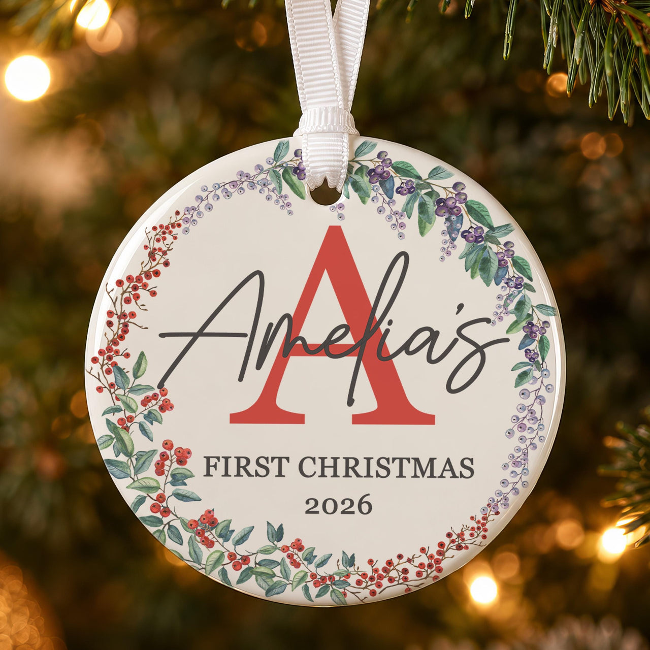 First Christmas bauble: ceramic ornament with a red initial A, berry wreath and Amelia's First Christmas 2026