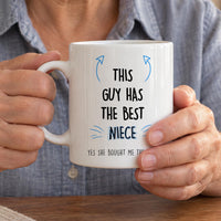 Uncle mug from a niece: white mug with blue arrows and the slogan THIS GUY HAS THE BEST NIECE, held in two hands