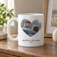 White 11oz heart photo mug on a wooden shelf next to flowers