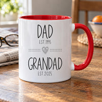 Personalised Dad to Grandad mug: white mug with red handle reading DAD EST.1995 and GRANDAD EST.2025 with a heart